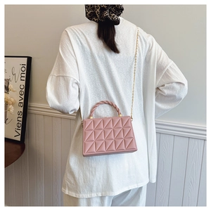 Pink geometric embossed handbag with woven handle and gold chain strap worn by model