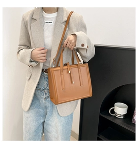 Detailed view of brown leather tote bag with sturdy handles and adjustable strap