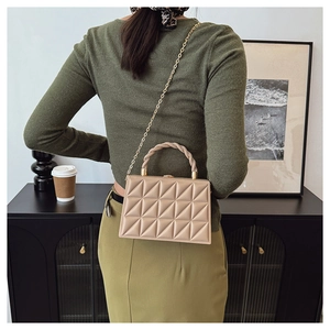Detailed close-up of beige quilted crossbody bag with woven handle and gold chain strap