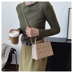 Detail of beige quilted crossbody box bag with gold chain strap and top handle