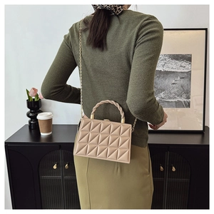 Detail of beige quilted geometric handbag with woven handle and gold chain strap