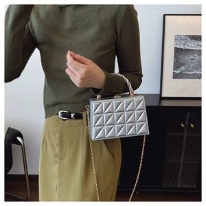 Detail of silver box bag featuring geometric quilted texture and metallic chain strap