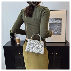 Detail of silver quilted rectangular handbag with gold chain strap and woven handle