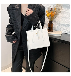 Detailed view of white faux leather tote bag with handles and thin shoulder strap