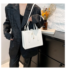 Close-up of minimalist white PU leather handbag with sleek handles and golden hardware