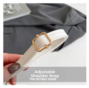 Detail of adjustable white leather shoulder strap with gold metal buckle and stitching