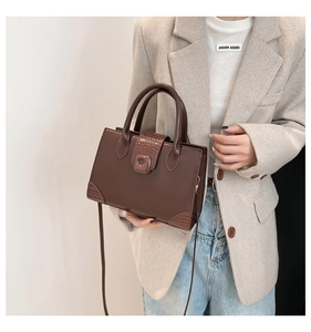Detail of a dark brown square handbag featuring textured crocodile pattern on the corners