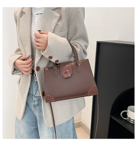 Detail of dark brown box bag with crocodile embossed leather accents worn over a grey blazer