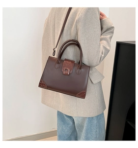 Detail view of brown crocodile texture leather bag styled with a beige herringbone blazer
