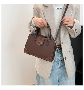 Detail showing deep brown crossbody bag with crocodile pattern and adjustable strap