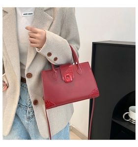 Detail view of red box bag with crocodile embossed leather panels and square clasp