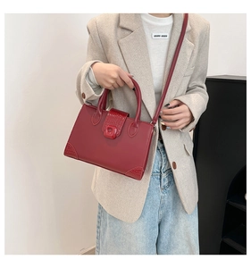 Detail shot of wine red crocodile embossed leather handbag styled with a blazer