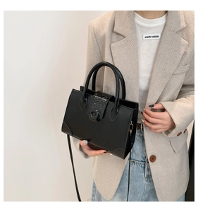 Close-up of structured black square handbag with crocodile texture and dual handles