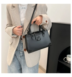 Detail showing classic black handbag with textured crocodile pattern on corners and flap