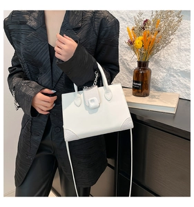 Detail of white rectangular bag with crocodile texture stitching and silver chain handle