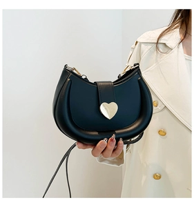 Gros plan d'un sac demi-lune noir avec une boucle décorative en métal doré en forme de cœur