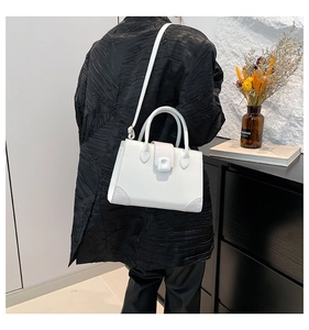 White square handbag with grey snakeskin texture trim and adjustable shoulder strap worn by model