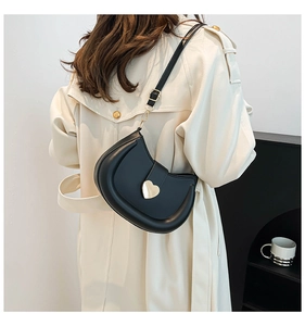 Détail d'un sac demi-lune en cuir noir avec boucle cœur dorée et bandoulière réglable