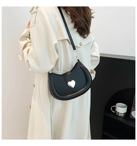 Détail du sac hobo avec boucle coeur argentée sur cuir noir au design incurvé élégant