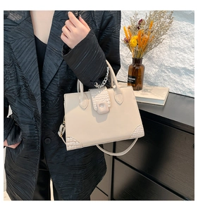 Chic beige tote bag featuring crocodile pattern details shown with a black blazer