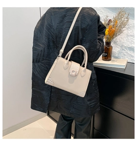 Detail of beige tote bag featuring crocodile pattern texture and square magnetic buckle