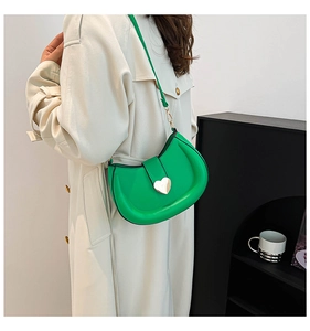 Détail du sac croissant vert arborant une boucle dorée signature en forme de cœur