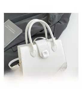 Detail view of white crocodile pattern shoulder bag with a square buckle and handle