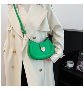 Détail du sac besace vert clair avec fermoir cœur doré et bandoulière réglable sur le côté