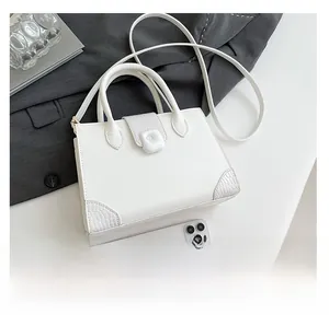 Detail view of white crocodile pattern square bag with twin handles and crossbody strap