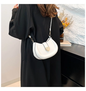 Détail du sac croissant blanc avec fermoir coeur doré et bordure noire élégante
