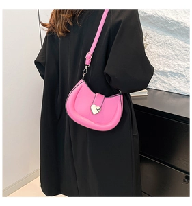 Détail d'un sac bandoulière demi-lune rose vif avec une grande boucle coeur argentée