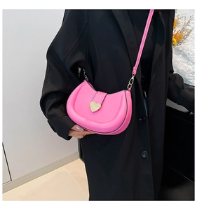 Sac sous le bras rose en forme de croissant avec fermoir cœur sur un manteau noir