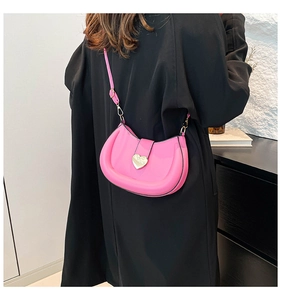Vue détaillée d'un sac selle rose avec une boucle cœur dorée et une bandoulière en cuir PU