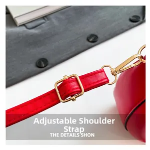 Détail d'une bandoulière réglable en cuir rouge avec boucle métallique dorée