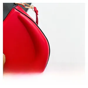 Gros plan du sac en cuir rouge montrant la finition des bords et le crochet en métal doré