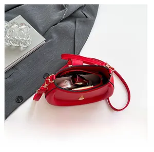 Vue intérieure du sac selle rouge montrant la poche zippée, le fermoir aimanté et les cosmétiques