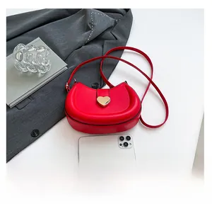 Détail du sac demi-lune rouge avec fermoir cœur et smartphone pour comparaison de taille