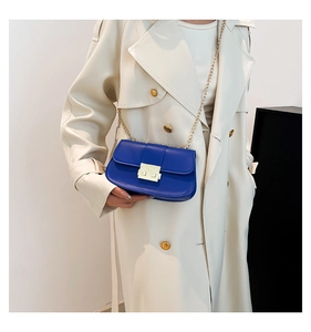 Détail d'un sac bandoulière en cuir bleu roi avec fermoir doré et fine chaîne