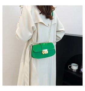 Mannequin portant un sac bandoulière vert vif avec chaîne dorée et finition brillante