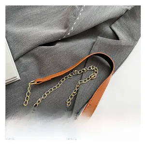Détail de la bandoulière en cuir marron avec chaîne en métal doré sur un sac rétro