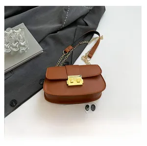 Sacoche vintage marron avec boucle dorée et bandoulière chaîne à côté d'un téléphone pour taille