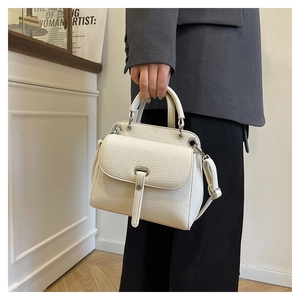 Detail of cream lychee texture leather bag with silver metal hardware and buckle strap