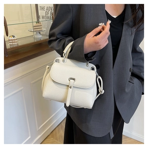 Model wearing white lychee grain leather crossbody bag with silver clasp in cafe setting