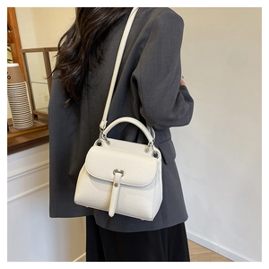 Back view of a white textured leather crossbody bag styled with a grey blazer