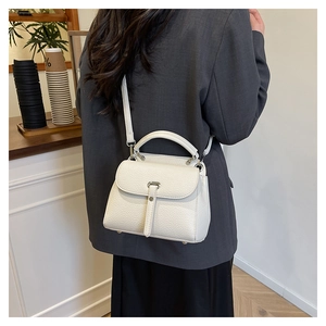 Rear view of model wearing a white lychee grain leather crossbody bag in a cafe setting