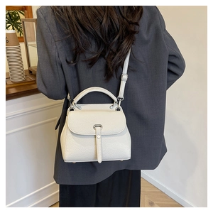 Close-up of cream lychee pattern leather handbag with silver hardware on gray blazer