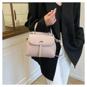 Close-up of light pink litchi grain leather bag with silver metal decorative buckle
