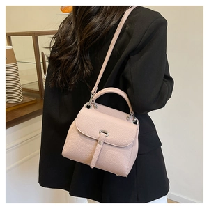 Close-up of pink lychee grain leather handbag with silver hardware in a cafe setting