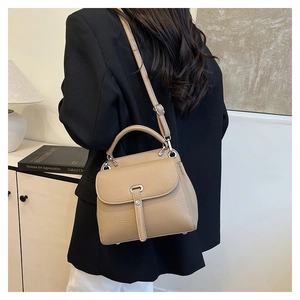 Close-up of beige lychee grain leather bag with silver buckle and crossbody strap