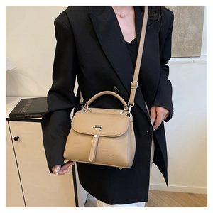 Close-up of beige lychee leather crossbody bag styled on a black blazer for a chic look